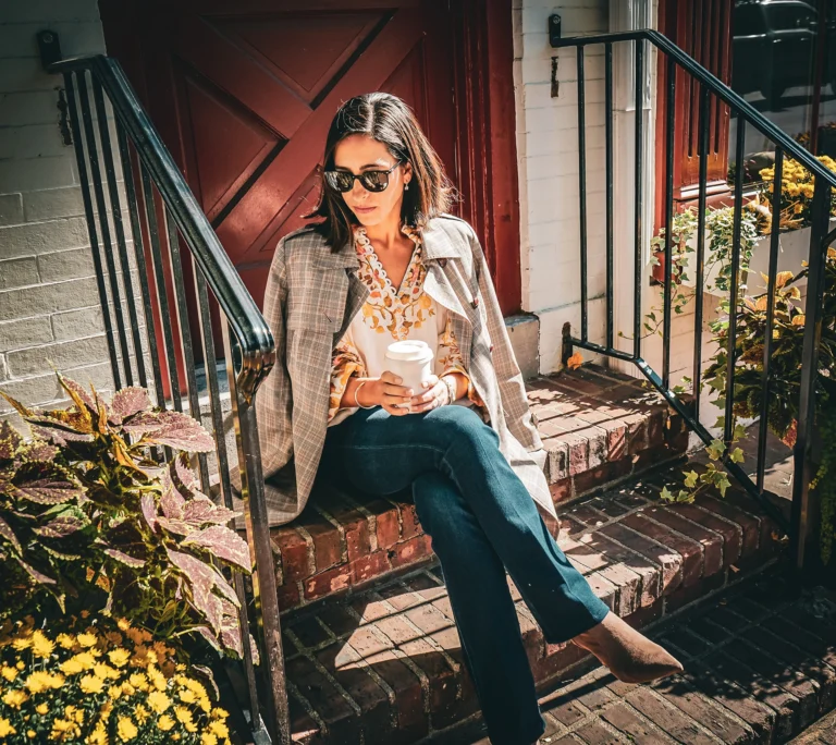 a woman sitting on steps holding a cup of coffee